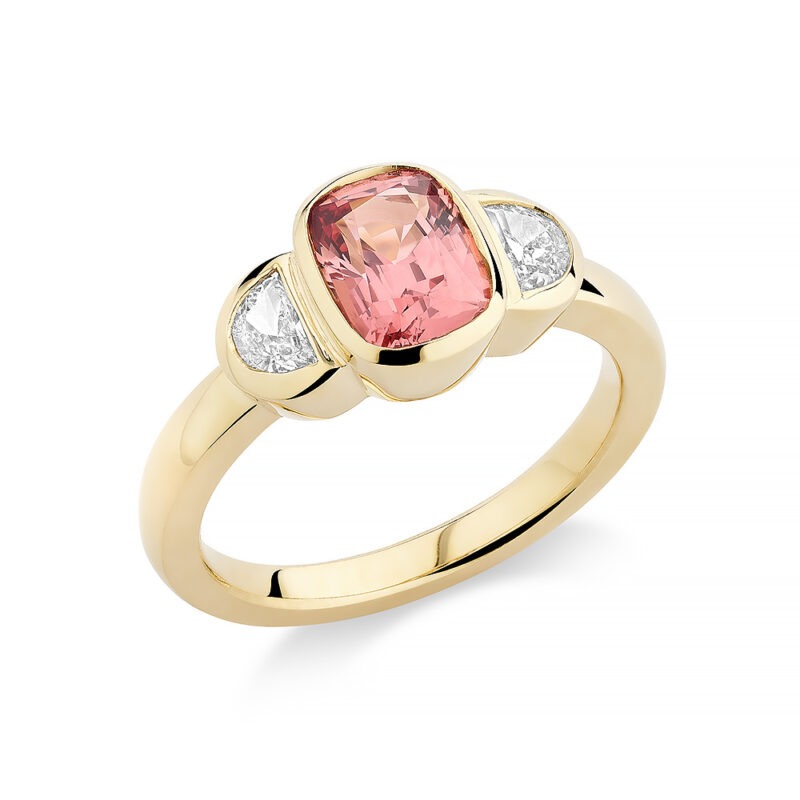 18k gold bezel set 3 stone ring with a peach spinel and diamonds