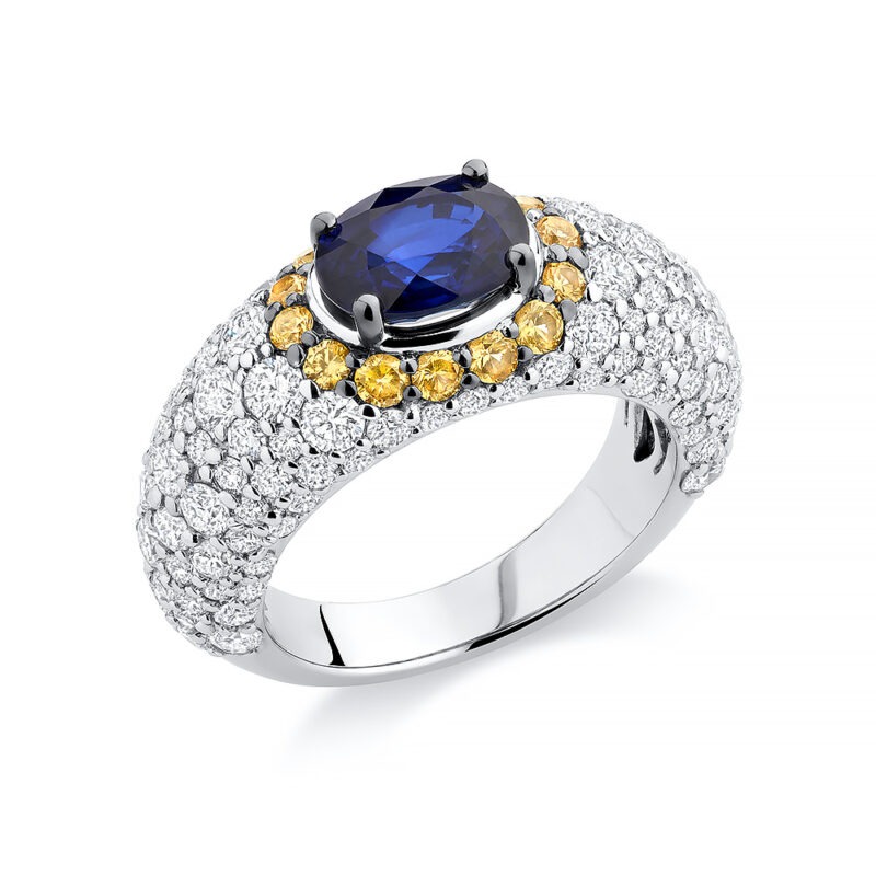 18k white gold cocktail ring set with an unheated blue sapphire, encased in a halo of yellow sapphires and accented with diamonds